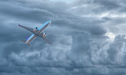 Fototapeta na wymiar White passenger airplane in the stormy clouds - Travel by air transport