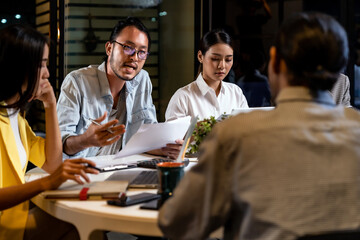 Working late, interracial asian business team brainstorm idea meeting.