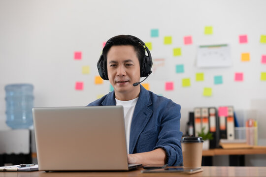 Asian Senior business man wearing earphone meeting with business team via video conference call at Home or Co-Working Space or Startup Office