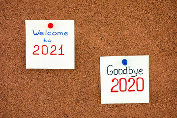 Two notes with phrases Goodbye 2020 and Welcome to 2021 on cork board.