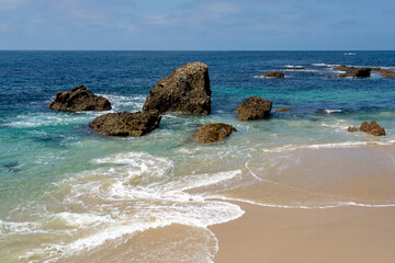 Seascape of ocean, beach and offshore rocks in the shallows at Woods Cove, in Laguna Beach, California.