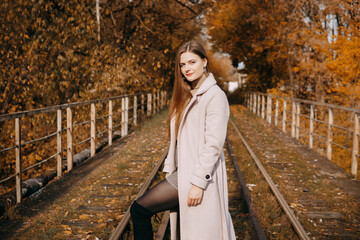 beautiful long-haired woman walks through the autumn streets. Railway, autumn, woman in a coat.