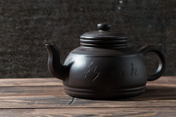 dark clay teapot on a wooden background
