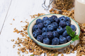 fresh juicy blueberries and homemade granola on white background, closeup