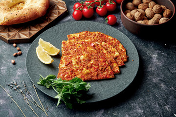 Turkish cuisine dish - pide with minced meat and tomatoes on a black plate. Turkish lahmajun, close up, selective focus