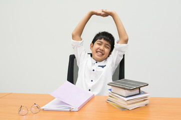 Asian boy student is showing stretch lazily while he is studying in the classroom.A young man stretch oneself during reading a book.