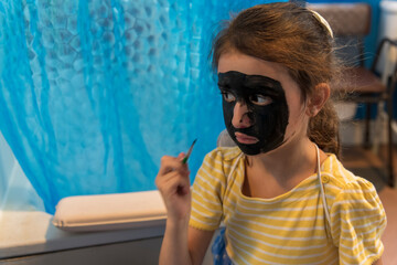 A young girl from poor deprived family is entertaining herself by face painting