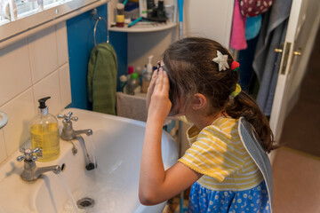 A young girl from poor deprived family is entertaining herself by face painting