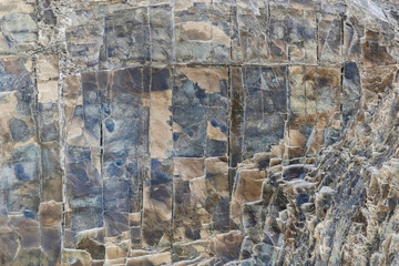 Rough texture of mountain wild stone. Marble. Granite. Stone abstraction. Mountain stone. The rough surface of an ancient mountain. Grunge texture. Laminated surface. Abstract grunge background.