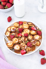 Fototapeta na wymiar Mini pancakes with strawberries on a light background. Tasty breakfast. Food trending. Baby food