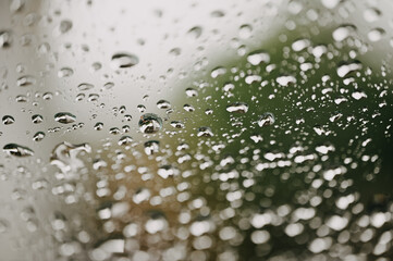 Soft focus rain drops on car glass and light bokeh background view in car.