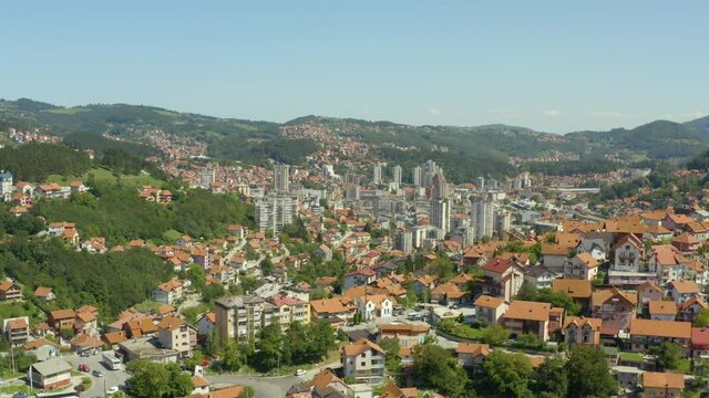 Aerial shot Uzice Serbia. A drone is a video of a city that is surrounded by mountains with forests and peaks where we see houses, streets, landscape, downtown, and many red roofs.