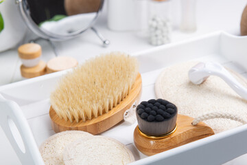 Obraz na płótnie Canvas Dry lymphatic drainage massage wooden brushes, derma mezoroller and loofah pads for face and body skin care on a white tray. Bathroom treatments. Homemade care. Natural beauty and zero waste concept.