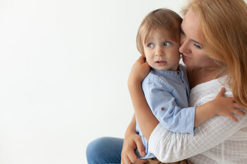 mom and son 2 years old sitting hugging on a white background