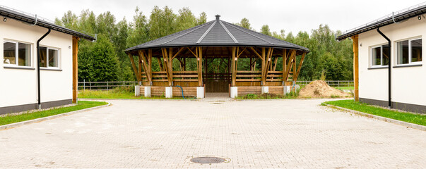 Lunge ring arena for horse training, outside entrance view. Circle equestrian building with roof.