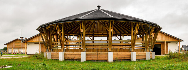 Lunge ring arena for horse training outside view. Circle equestrian building with roof. Modern equestrian round pen place.