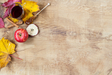 Brownish wooden table with natural autumn decoration, tea glass, cinnamon sticks and apple and candy sugar background. Autumn composition thanksgiving diy jewelry natural ecology design