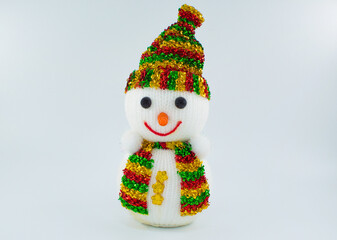 Cristmas soft toy of a snowman in a multicolored scarf and hat.