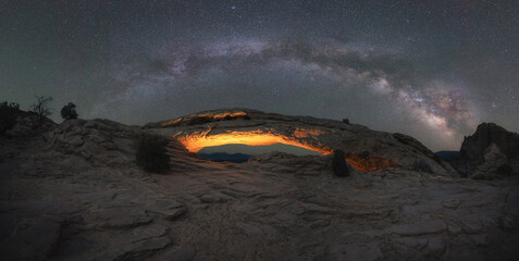 Fototapeta na wymiar Milky Way Panorama over Mesa Arch lit at night