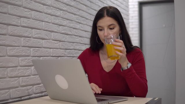 Woman freelancer working with laptop, drinking orange juce, remote work, home