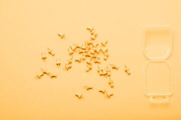 Scattered yellow push pins on yellow background