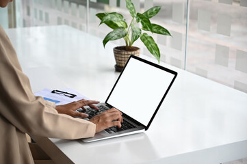 Cropped shot female typing mockup laptop computer on simple workspace.