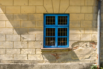 Fototapeta na wymiar Window with blue frame and lattice in old building wall (former hospital). Architectonic details of abandoned buildings. Maciejowice, Poland, Europe.