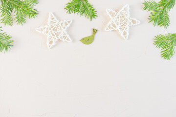New Year and Christmas flat lay in pastel neutral colors: wooden decorative stars, fir branches, wooden figurines of birds on light background. Copyspace, minimalism, top view