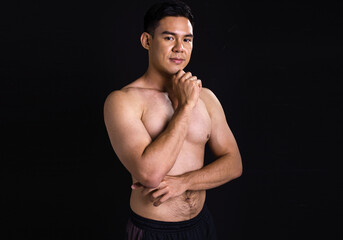 Fototapeta na wymiar Portrait of asian muscular man standing on black background