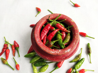 Red and Green chilli in a Red colored crock (mud made pot) in a white background
