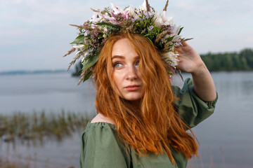 Slavic beauty with a flower wreath on her head in the lap of nature. Ancient pagan origin celebration concept. Summer solstice day. Mid summer. Ancient rituals.