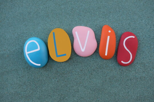 Elvis, masculine given name composed with multicolored stone letters over green sand
