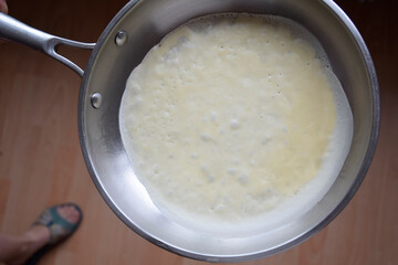 Cooking a pancake in hot frying pan.  Top view. Flat lay. Cooking process. Pancakes recipe. 