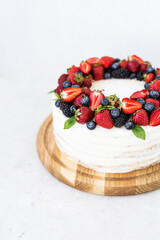 Rustic cake with fresh berries. Delicious fresh cake on a white background. Strawberry cake with blueberries and mint. Blueberry vanilla cream cake
