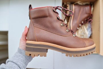 New womens leather brown waterproof winter boots in hands of female