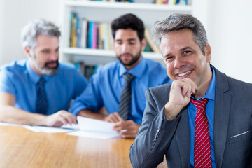 Handsome elderly businessman with motivated team at office