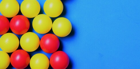 Small colored balls, yellow and red, on a blue background, space for text