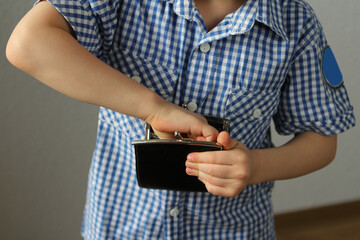 kid holds a wallet and takes out with his hand, the concept of pocket money, theft, shopping