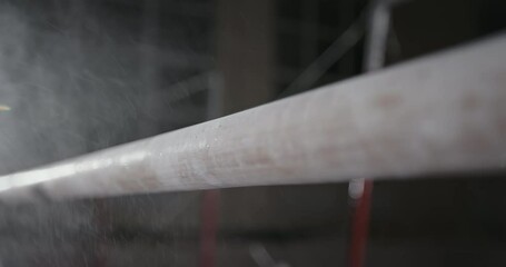 Closeup cloud of magnesium dust falling on shabby bar during gymnastic training in gym