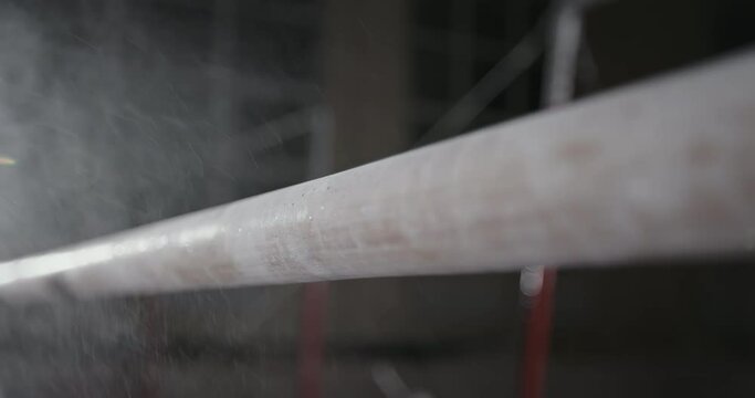 Closeup cloud of magnesium dust falling on shabby bar during gymnastic training in gym