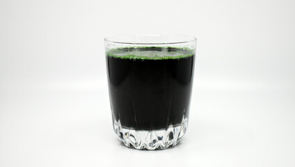 Green spirulina solution and spirulina powder in glass beakers