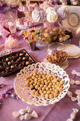 Decorating the festive table. On the table are sweets, marshmallows, nuts. The table is decorated with a purple tablecloth.