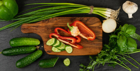 Obraz na płótnie Canvas Sliced Cucumber with Green Vegetables on Rustic Cutting Board