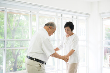 Fototapeta na wymiar joyful senior asian retired couple is dancing and enjoying the music in the living room at home, health concept