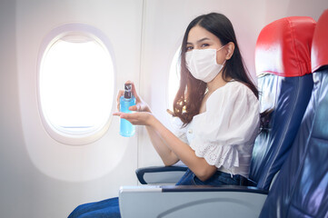 A traveller woman is wearing protective mask is washing hands with alcohol gel onboard , New normal travel concept