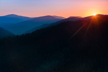 Great view of colorful sunrise in the mountains backlight glow against the sunlight with sun flare and bokeh. Concept of the awakening wildlife, emotional experience in your soul.