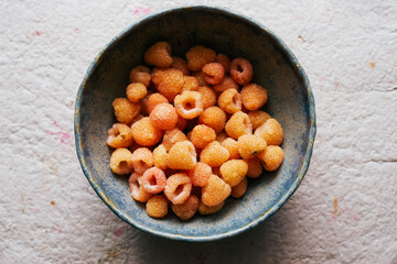Ripe healthy yellow raspberries in a bowl vegan food
