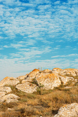 Rocks with orange moss and blue cloudy sky 