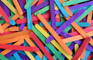 Multicolored popsicle sticks in bulk in shades of purple red light blue yellow orange green for desktop background e