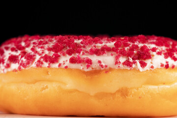 Close-up view of pink glazed donut with sprinkles.